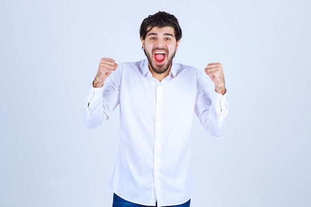 Man in white shirt showing his fists and feeling successful