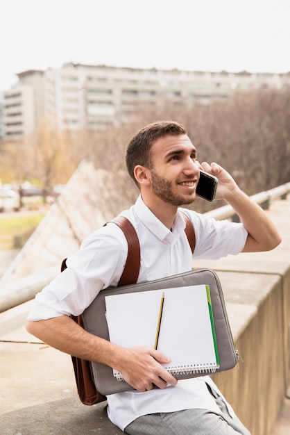 Man in white shirt talking on phone and looking up