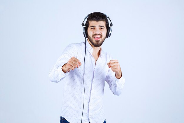 Man in white shirt wearing headphones and enjoying the music