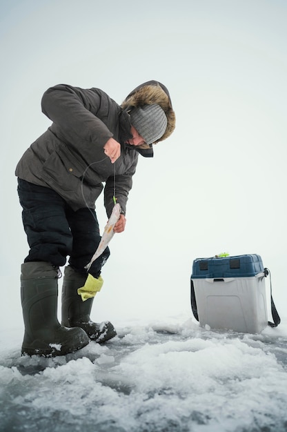 Man in winter clothes fishing alone outside