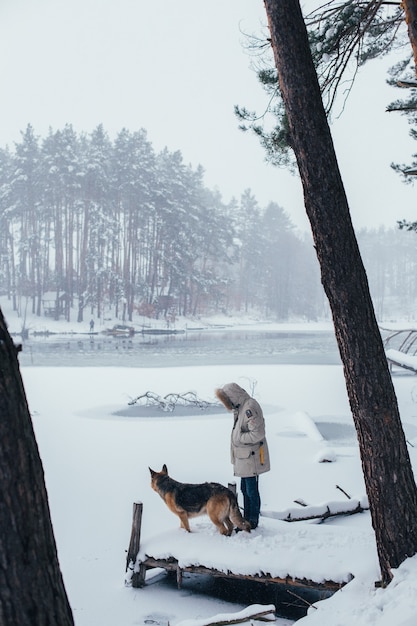 Free Photo man in winter coat in forest with shepherd dog