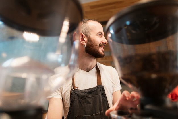 Man with apron working and defocused coffee holders