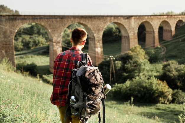 Free photo man with backpack in green field