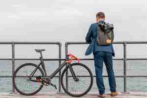 Free photo man with backpack standing next to his bike