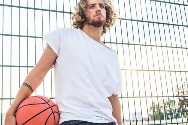 Man with basketball standing in front of fence