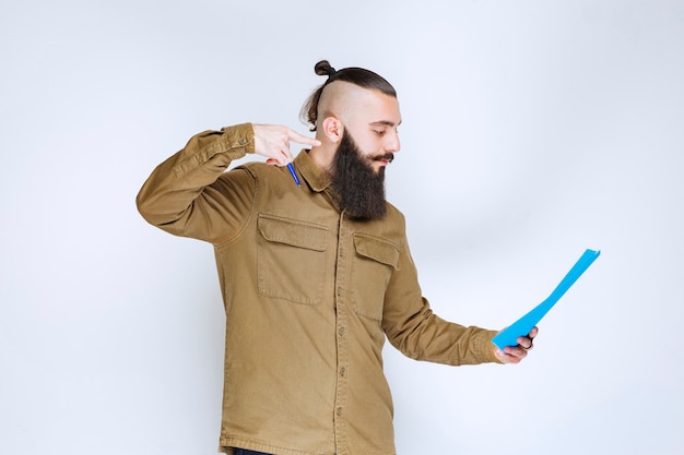 Man with beard checking the project list and marking notes or corrections.