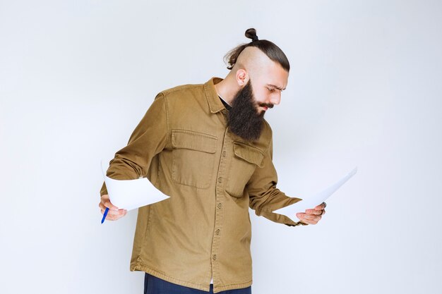 Free photo man with beard checking the project list and marking notes or corrections.