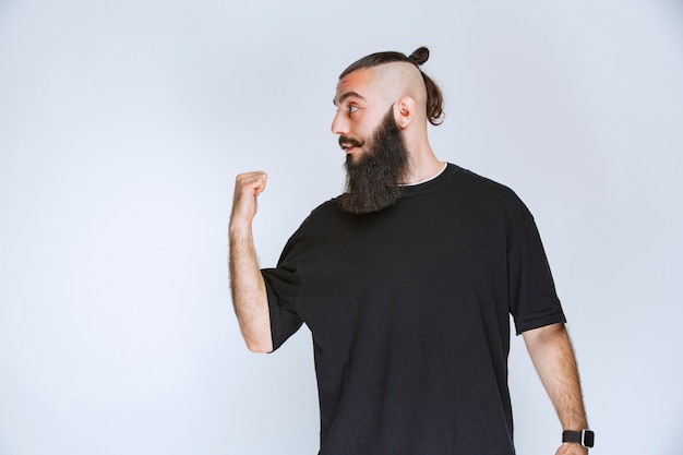 Free photo man with beard demonstrating his arm muscles and fists.