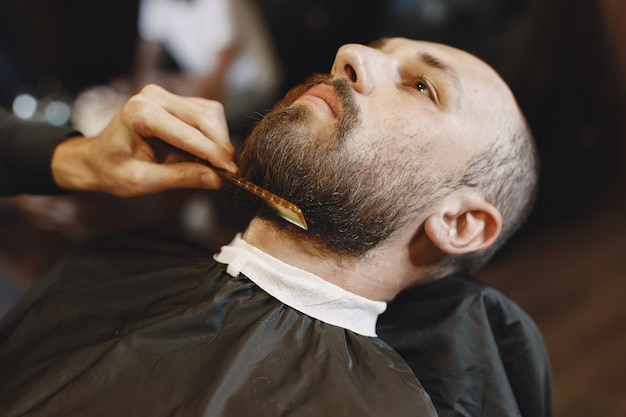 Man with a beard. Hairdresser with a client. Man with a comb and scissors