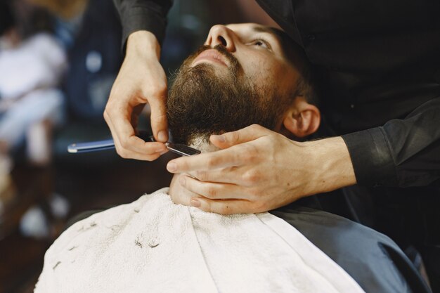 Man with a beard. Hairdresser with a client. Man with a shave.