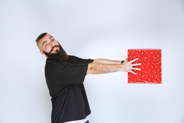 Free Photo man with beard holding a red gift box      