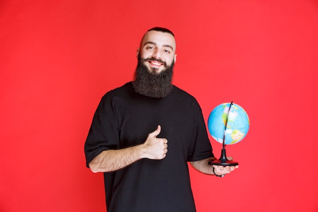 Free photo man with beard holding a world globe and enjoying it.