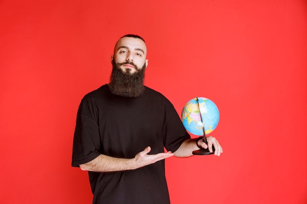 Man with beard holding a world globe.