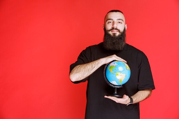 Man with beard holding a world globe.