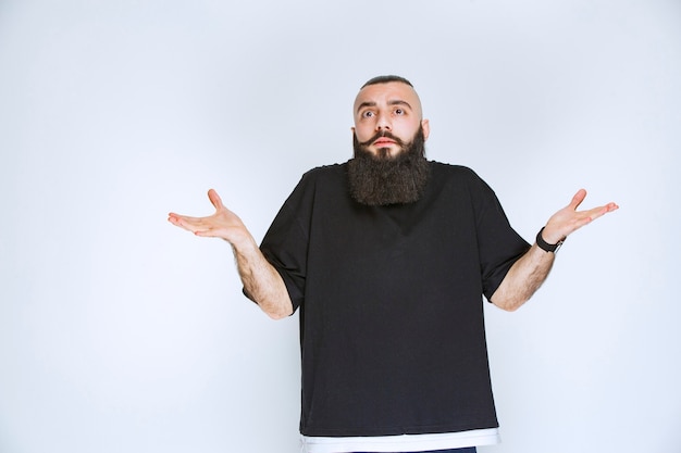 Free Photo man with beard looks confused and hesitating. 