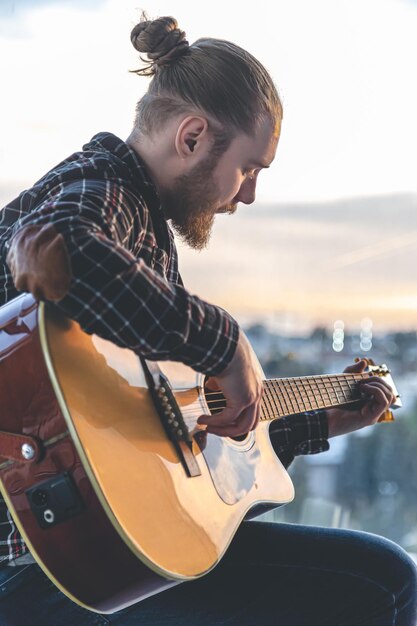 A man with a beard plays the acoustic guitar