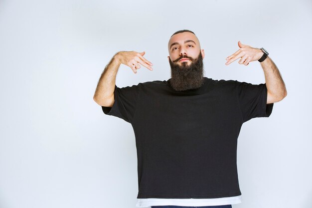 Man with beard pointing at himself. 