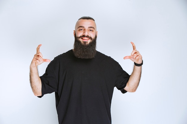 Free Photo man with beard showing the dimensions of an object.