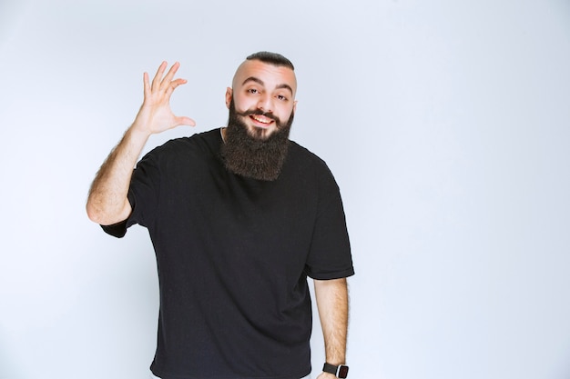 Man with beard showing the dimensions of an object. 