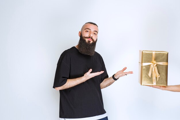 Man with beard showing his golden wrap gift box. 