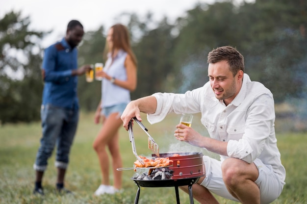 Free photo man with beer attending barbecue for friends