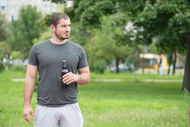 Man with beer looking away in park