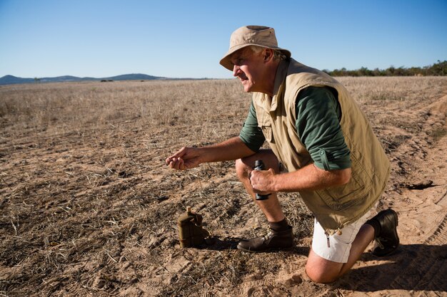 Man with binocular kneeling on landscape