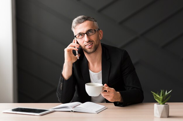 Man with black jacket looking away and holding a cup