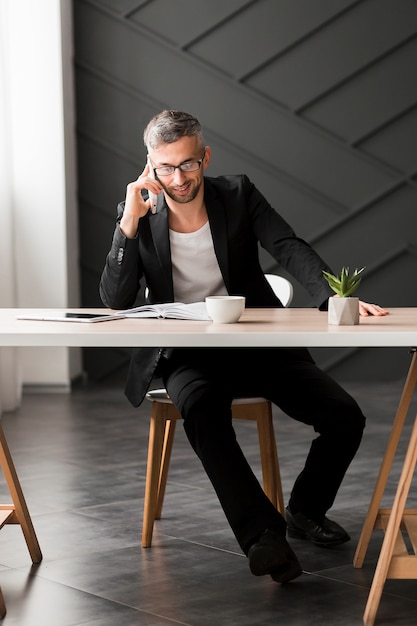 Free photo man with black jacket talking on the phone indoors