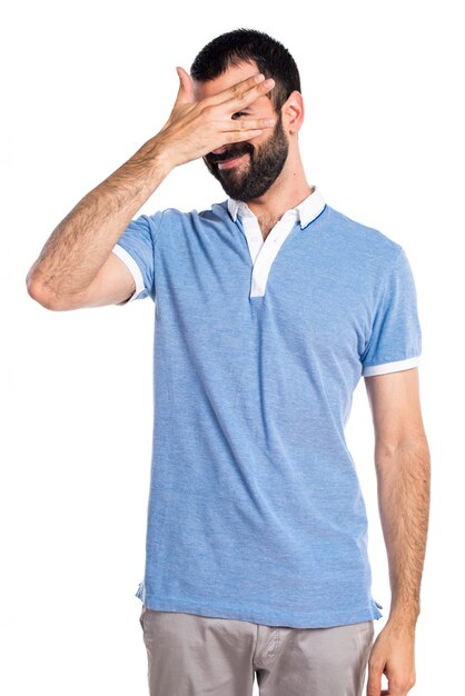 Man with blue shirt covering his face