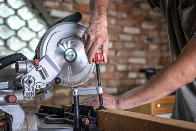 A man with a board and miter saw close up, concept building and repair.