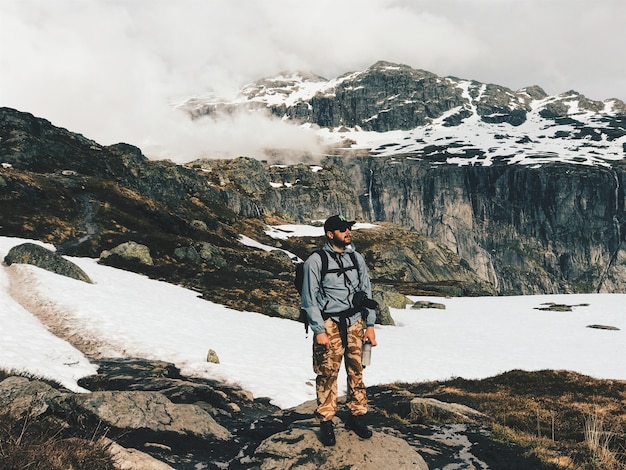 Free Photo man with a camera and rucksack stands before the mountains covered with snow