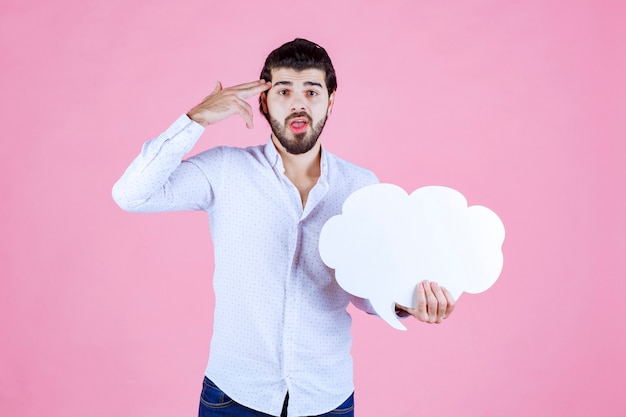 Free Photo man with a cloud shape ideaboard looks thoughtful. 