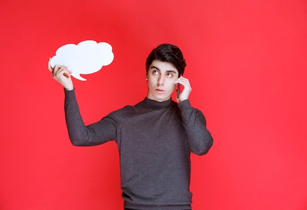 Free photo man with a cloud shape thinkboard talking to the phone