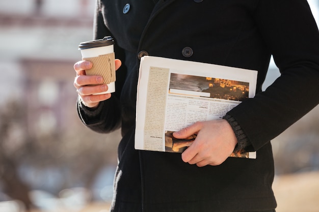 Man with coffee and newspaper walking in the city