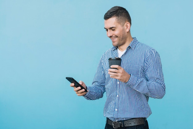 Man with coffee and smartphone in urban environment