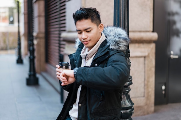 Man with cup of coffee looking at his watch