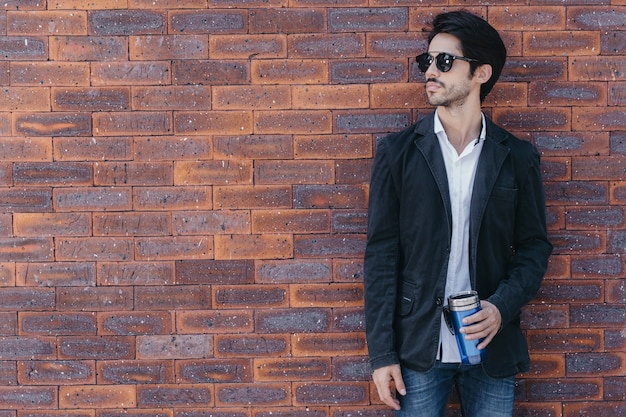 Man with cup near brick wall