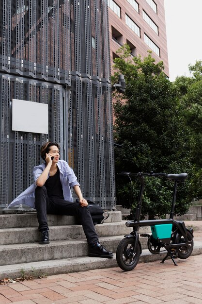 Man with electric bicycle in the city talking on the phone