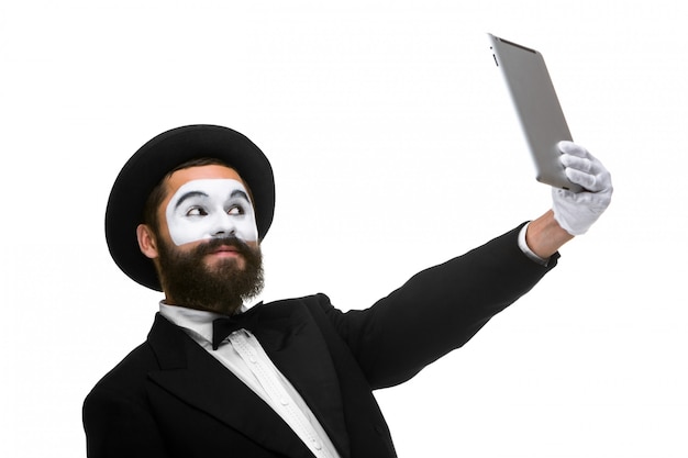 Man with a face mime working on a laptop isolated on a white 