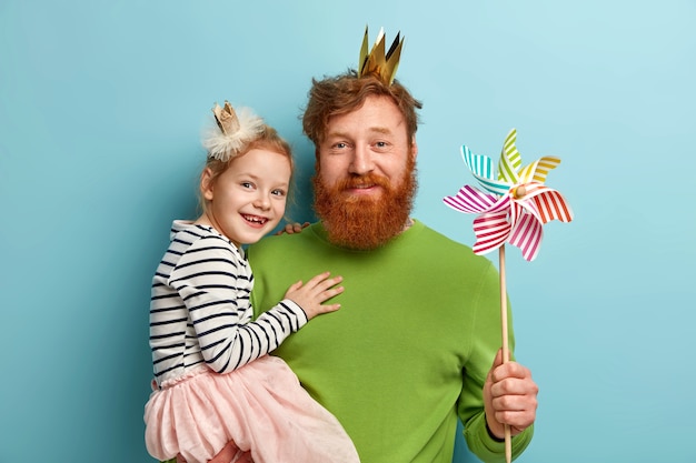 Free photo man with ginger beard and his daughter with party accessories