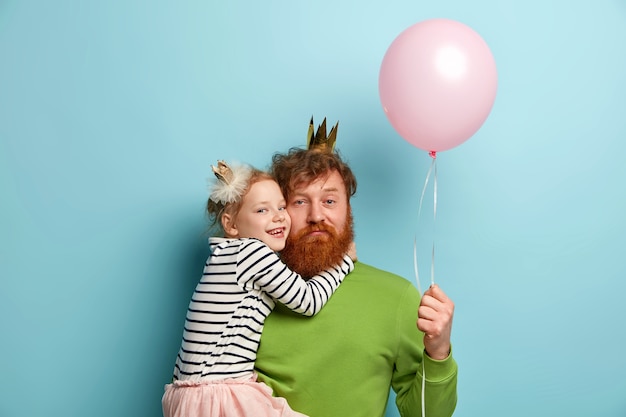 Free photo man with ginger beard and his daughter with party accessories