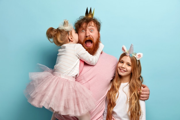 Free photo man with ginger beard and his daughters with party accessories