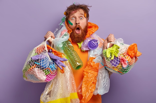 Free photo man with ginger beard holding bags with plastic waste