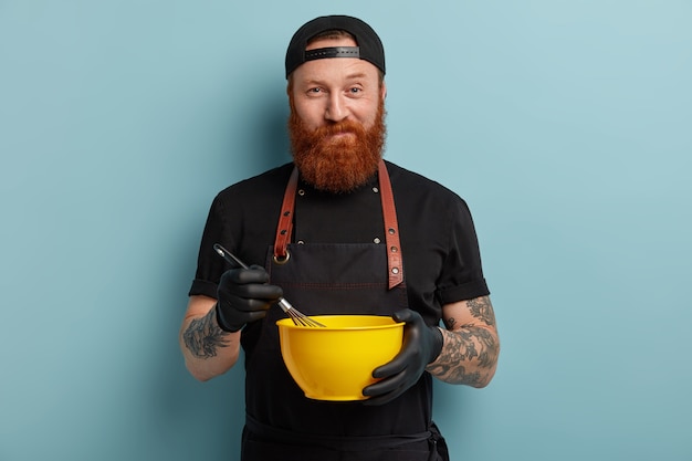 Free photo man with ginger beard wearing apron and gloves holding bowl