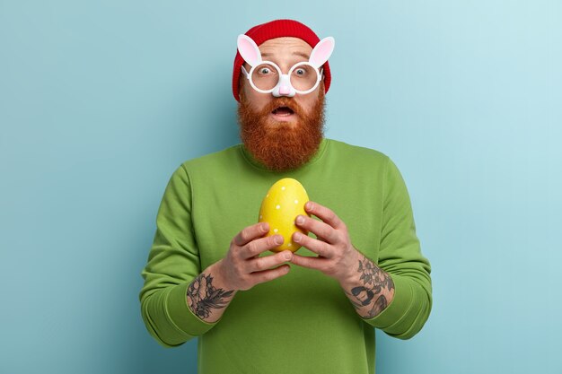 Man with ginger beard wearing colorful clothes and bunny ears eyeglasses