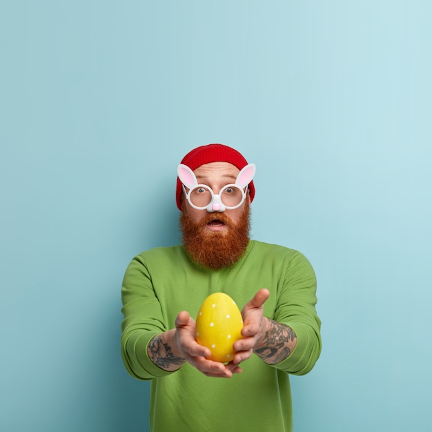 Man with ginger beard wearing colorful clothes and bunny ears eyeglasses