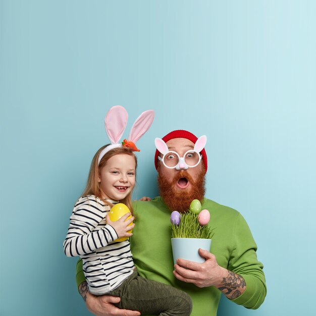 Man with ginger beard wearing colorful clothes holding his daughter