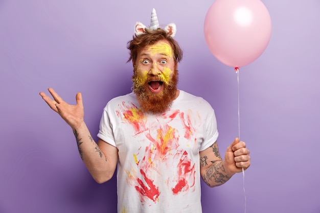 Free photo man with ginger beard wearing unicorn headband and dirty t-shirt