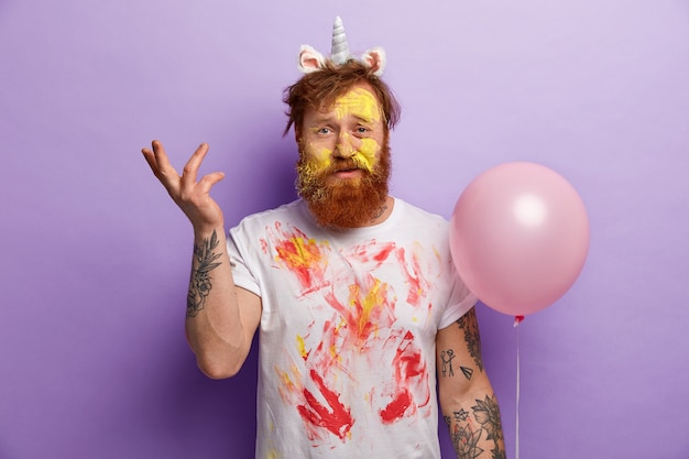 Free photo man with ginger beard wearing unicorn headband and dirty t-shirt